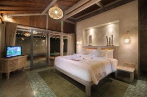 a bedroom with a large bed and a television at Casa Batu Belig in Seminyak