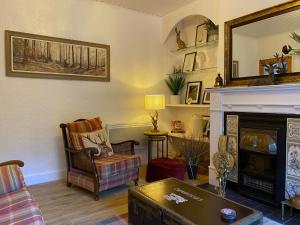 sala de estar con chimenea y silla en MacLeen Cottage, en Arrochar