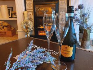 two champagne glasses and a bottle of wine on a table at MacLeen Cottage in Arrochar
