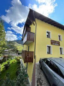 una casa amarilla con un coche aparcado delante de ella en Appartamento alle porte di Bormio en Valdisotto