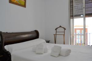 een slaapkamer met een bed met witte lakens en een stoel bij SunShine San Pablo in Córdoba