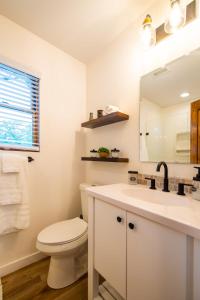 Baño blanco con aseo y lavamanos en The Wren Treehouse 15 MIN to Magnolia Baylor, 