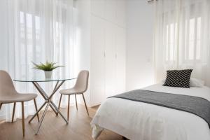 sypialnia z łóżkiem, stołem i krzesłami w obiekcie One&lux Puerta Osario w Sewilli