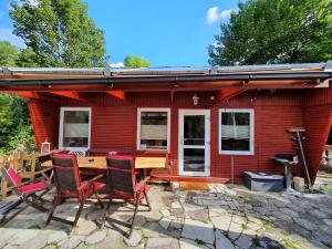 ein rotes Haus mit einem Tisch und Stühlen davor in der Unterkunft Ferienhaus "Am Hexenstieg" in Höhlenort Rübeland