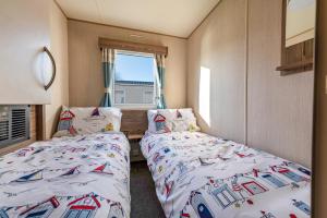 een slaapkamer met 2 bedden en een raam bij Waterside, Thorpe Park Cleethorpes Static Caravan in Cleethorpes