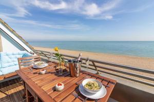 a table with plates of food on a balcony overlooking the beach at The luxury Beach property - Oceanbreeze in Sandgate