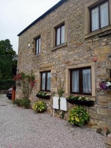 un edificio de piedra con ventanas y flores. en Charming, wonderfully cosy one bedroom apartment en Giggleswick