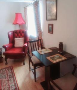 a living room with a table and a red chair at Charming, wonderfully cosy one bedroom apartment in Giggleswick