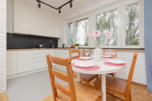 a white kitchen with a white table and chairs at Warsaw Magellana Apartment by Renters in Warsaw