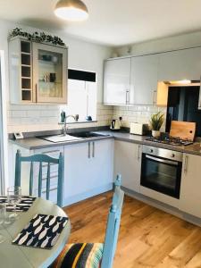 una cucina con armadi bianchi e un tavolo con tavolo. di Cosy 3 bedroom house close to beach a Lowestoft