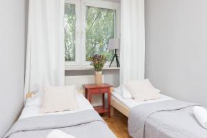 two beds in a room with a window at Warsaw Magellana Apartment by Renters in Warsaw