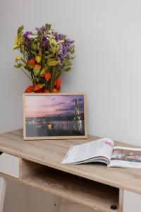 a vase of flowers and a book on a table at Warsaw Magellana Apartment by Renters in Warsaw