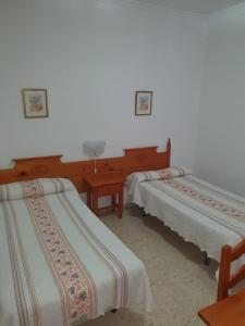a group of three beds in a room at Pensión los Ángeles in La Puebla de Cazalla