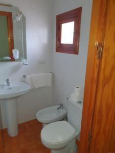 a white bathroom with a toilet and a sink at Pensión los Ángeles in La Puebla de Cazalla