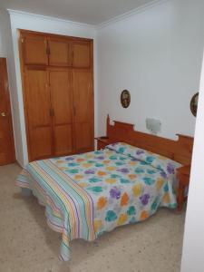 a bedroom with a bed with a colorful comforter at Pensión los Ángeles in La Puebla de Cazalla
