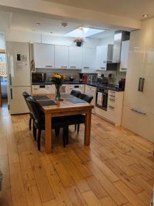una cocina con mesa de madera con sillas y una cocina con armarios blancos. en Cambridge city centre immaculate 2 bed apartment, en Cambridge