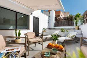 Magno Apartments Cabo Noval Luxury House في إشبيلية: فناء فيه كراسي وطاولة عليها برتقال