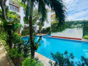 a swimming pool in front of a building with palm trees at Dong Xuan Hong Hotel in Phu Quoc