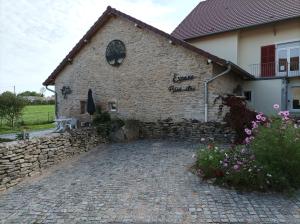 ein Backsteingebäude mit einer Steinmauer und einer Terrasse in der Unterkunft Gîte Massatho tout confort avec jardin in Fay-en-Montagne