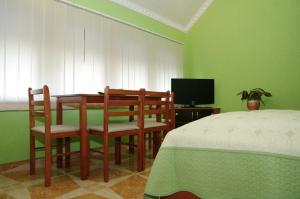 1 dormitorio con mesa, sillas y TV en Nefelejcs Apartman, en Gyula