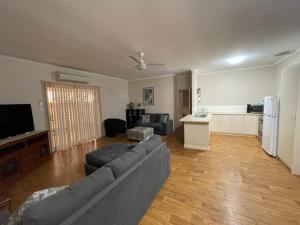a living room with a gray couch and a kitchen at Four bedroom House on Masters South Hedland in South Hedland