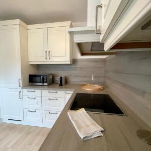 a kitchen with white cabinets and a sink at Hochfeld City Apartment in Tegernsee