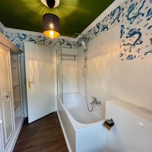 a bathroom with a tub and blue and white wallpaper at Hochfeld City Apartment in Tegernsee