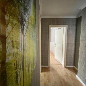 a hallway with a painting of trees on the wall at Hochfeld City Apartment in Tegernsee