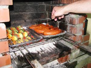 una persona está cocinando salchichas en una parrilla en E-Stay Noclegi w Bydgoszczy, en Bydgoszcz