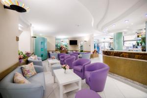Hotel Ariane - BEACHFRONT, Breakfast XXL & Brunch في ريميني: غرفة انتظار مع كراسي أرجوانية وطاولة