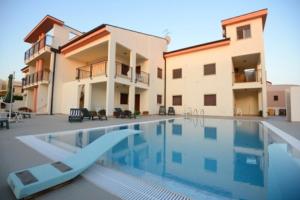 a villa with a swimming pool in front of a house at Lina apartments in Ginosa Marina +11 photos