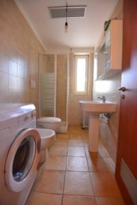 a bathroom with a toilet a sink and a washing machine at Lina apartments in Ginosa Marina