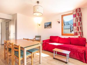 a living room with a red couch and a table at Vacancéole - Le Dôme des Rousses in Vaujany