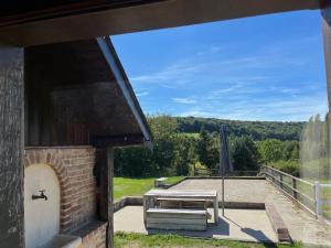 - une terrasse avec une table de pique-nique et un parasol dans l'établissement Le Gîte Marguerite - Calvados : vue panoramique sur la Normandie, à Hermival-les-Vaux