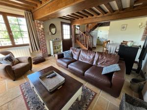 sala de estar con sofá de cuero y mesa en Le Gîte Marguerite - Calvados : vue panoramique sur la Normandie en Hermival-les-Vaux