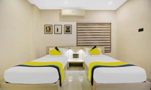 two beds in a room with white walls and yellow pillows at Itsy By Treebo - Transit Express in Kolkata