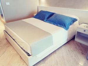 a white bed with blue pillows on top of it at EUROPA Hotel in Vasto