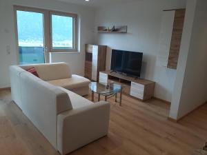 a living room with a white couch and a tv at Apart MountainView in Bruck am Ziller