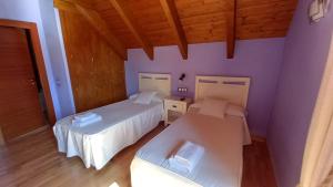 Habitación con 2 camas, paredes de color púrpura y suelo de madera. en Hostal Rural Casa Parda, en Tramacastilla de Tena