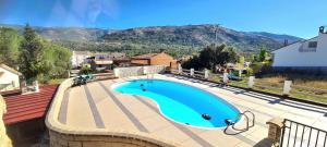 a swimming pool on a patio with mountains in the background at Casa la hijita in Navaluenga