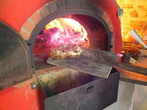 een pizza wordt bereid in een bakstenen oven bij Eisenmannhof in Gengenbach