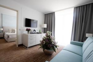 a hotel room with a bed and a couch and flowers at Thermal Hotel Visegrád in Visegrád