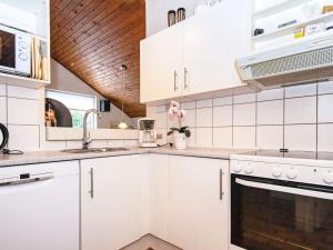 a kitchen with white cabinets and a wooden ceiling at 10 person holiday home in Glesborg in Fjellerup Strand