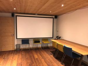 a large screen in a room with a table and chairs at Chalet La Clusaz, 9 pièces, 13 personnes - FR-1-304-219 in La Clusaz