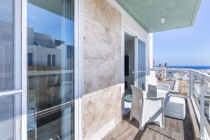 Un balcón con sillas blancas y vistas al océano. en Your home away from home - top floor apt close to the beach & entertainment, en Is-Swieqi