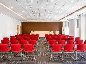 a conference room with red chairs and a podium at ibis Adana in Adana