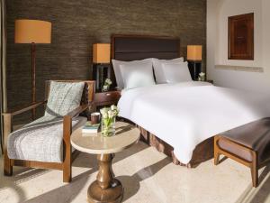 a bedroom with a bed and a chair and a table at Mövenpick Resort & Spa Dead Sea in Sowayma