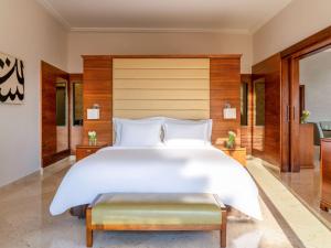 منتجع وسبا موڤنبيك البحر الميت في السويمة: غرفة نوم كبيرة مع سرير أبيض كبير ومقعد