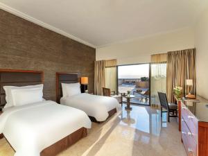 a hotel room with two beds and a desk with a desk at Mövenpick Resort & Spa Dead Sea in Sowayma