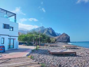 un edificio y bancos en una playa con una montaña en De Sebastian 2 - Frente al mar, en San Nicolás